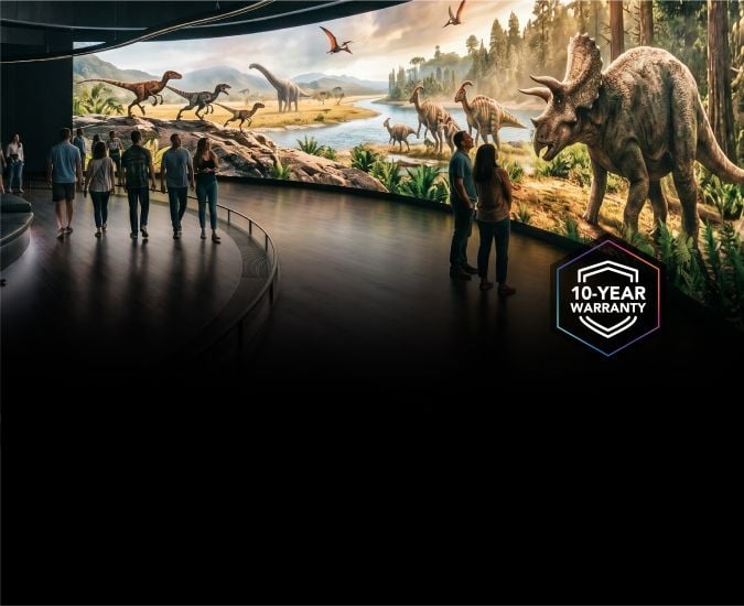 A large curver LED video wall showing images of dinosaurs and the jurassic period, with people walking in front and looking at it.